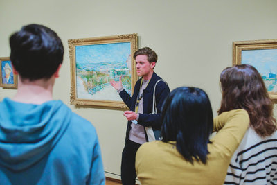 Museum docent Tyas Leeuwerink talks to highschool students about Vincent van Gogh's painting Montmartre: Behind the Moulin de la Galette during a guided tour. Photo: David Stegenga
