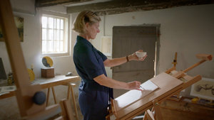 Video still of the workshop Drawing Peasant Life. The workshop teacher copies a cup in her hand in Vincent van Gogh's studio in Nuenen